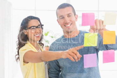 Smiling coworkers pointing sticky notes