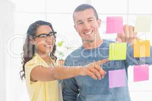 Smiling coworkers pointing sticky notes