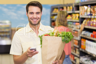 Portrait of smiling handsome man buying food products and using