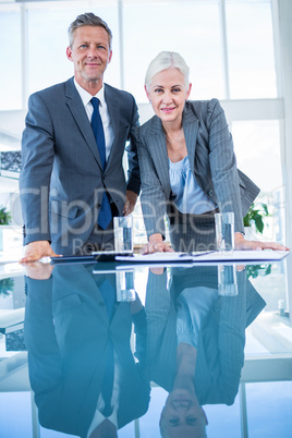 Business people looking at camera behind desk