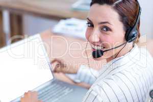 Portrait brunette businesswoman smiling using laptop and headpho