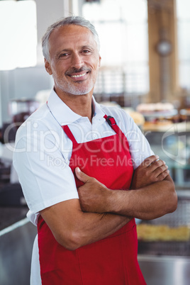 Happy barista smiling at camera with arms crossed