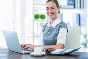 Happy businesswoman working on laptop computer and looking at ca