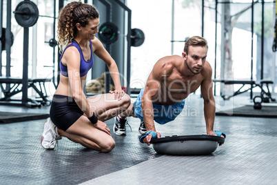 Muscular couple doing bosu ball exercises