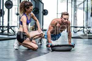 Muscular couple doing bosu ball exercises