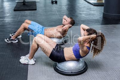 Muscular couple doing bosu ball exercises