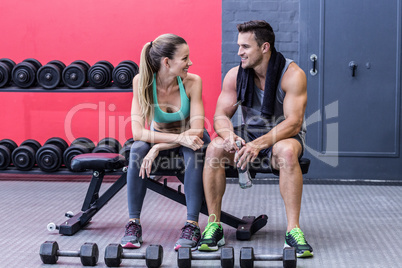 Muscular couple discussing on a bench