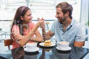 Young happy couple eating cake together