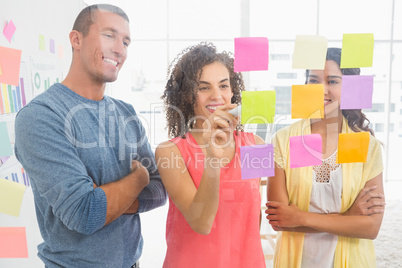 Smiling coworkers writing on sticky notes