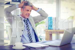 Furious businessman looking at laptop computer