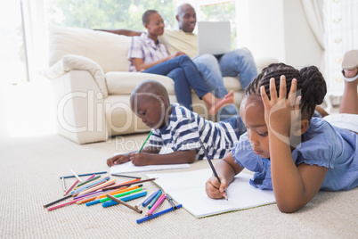 Happy siblings on the floor drawing