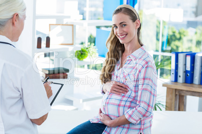 Pregnant woman smiling at camera on an examination table