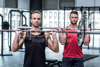 Muscular men lifting a barbell