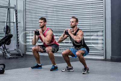Muscular men exercising with kettlebells