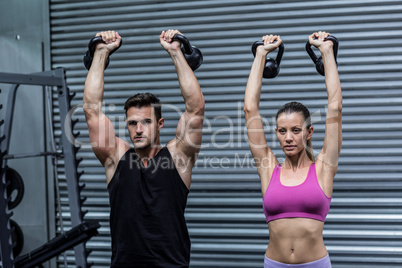 A muscular couple lifting kettlebells