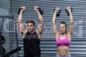 A muscular couple lifting kettlebells