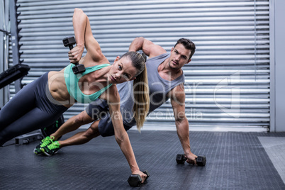 Smiling muscular couple doing side plank