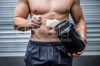 Muscular man making protein cocktail