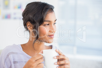 Casual businesswoman having a coffee at desk