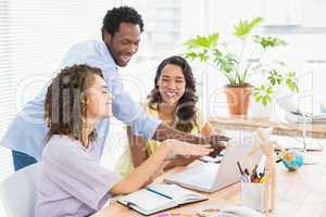 Happy coworkers using laptop at desk