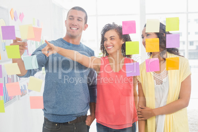 Smiling coworkers pointing sticky notes Smiling coworkers pointing sticky notes