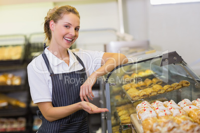 Portrait of a smiling blonde baker showing a pastry