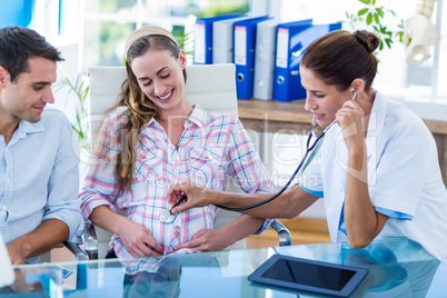 Doctor checking belly of pregnant woman with stethoscope