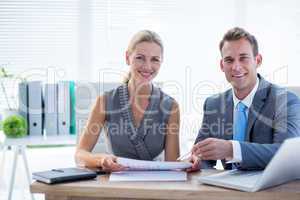 Happy colleagues working together on laptop and folder