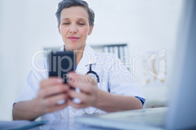 Happy doctor using her smartphone