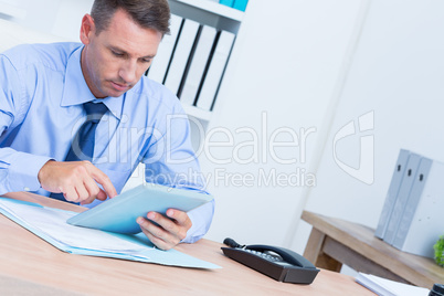 Serious businessman using digital tablet