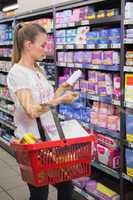 Woman taking a bottle of pills in the shelf of aisle