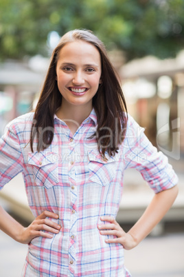 Pretty brunette with hands on hips smiling at camera