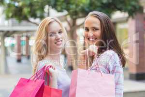 Happy women friends with shopping bags smiling at camera