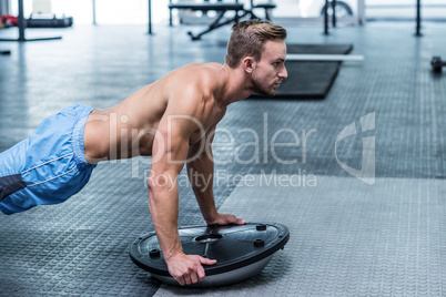 Muscular man doing bosu ball exercises