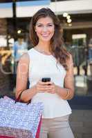 Portrait of smiling woman with shopping bags and smartphone look