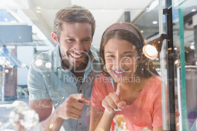 Young happy couple looking at jewellery from behind a window