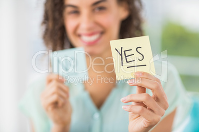 Smiling businesswoman holding yes and no sticks