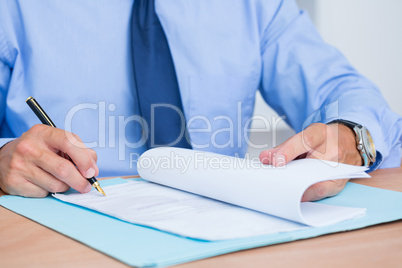 Smiling businessman reading a contrat before signing it