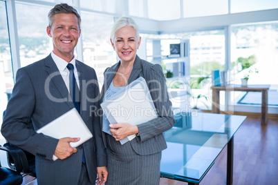 Happy business people looking at camera and holding shield