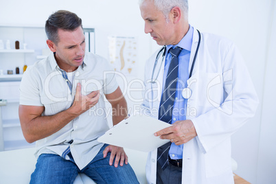 Doctor examining his patient and writing on clipboard