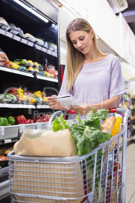 Smiling woman reading on his notepad in aisle