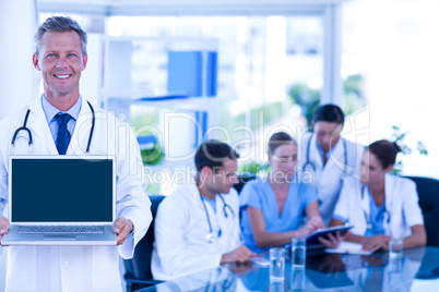 Doctor showing laptop with colleagues behind