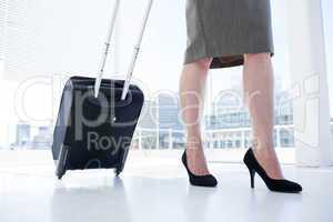 Businesswoman pulling her suitcase in the office