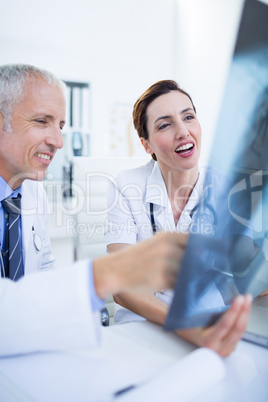 Smiling medical colleagues examining x-ray together