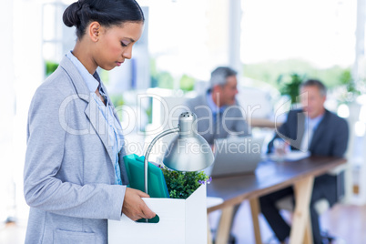 Businesswoman holding box with her colleagues behind her