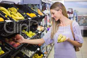 Smiling pretty blonde woman buying bananas