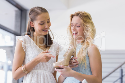 Happy women talking and holding a heel shoe