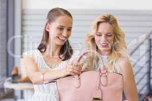 Two happy women looking at handbag
