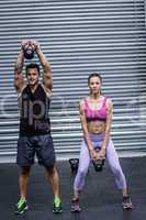 A muscular couple lifting kettlebells