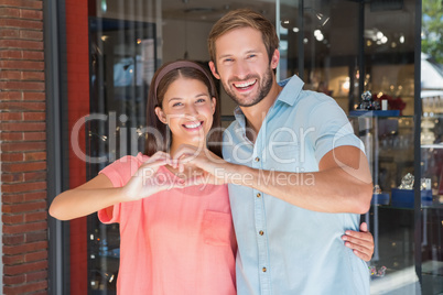 Young happy couple making a heart with their hands